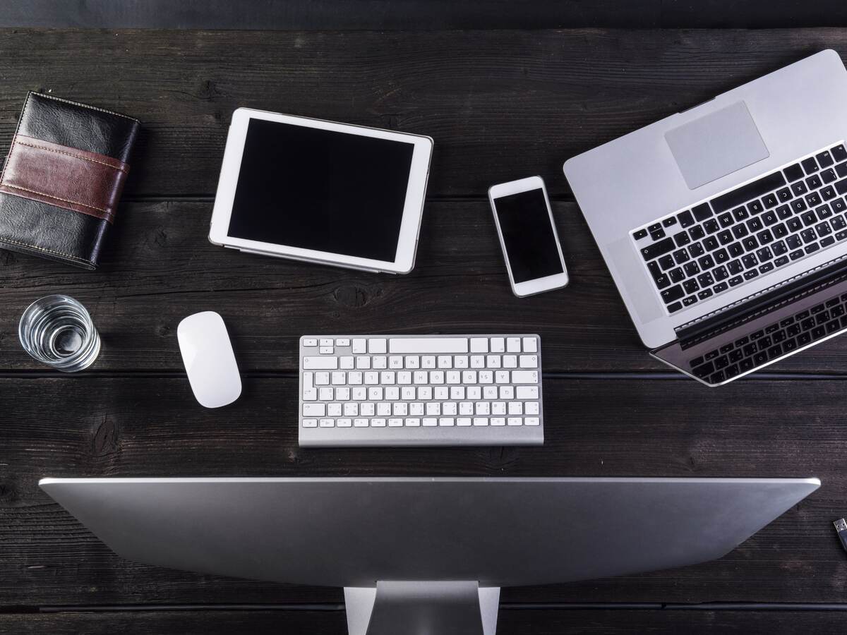 Desk with computer and various digital gadgets, overhead view.